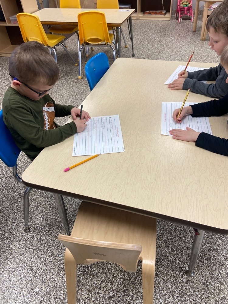 Pre-k class working on writing their names .